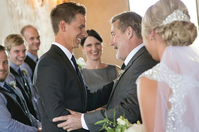 Female celebrant smiling as father of the bride and groom greet each other at the altar