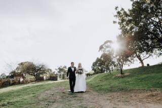 Bride walks down the hill towards outdoor wedding ceremony with father