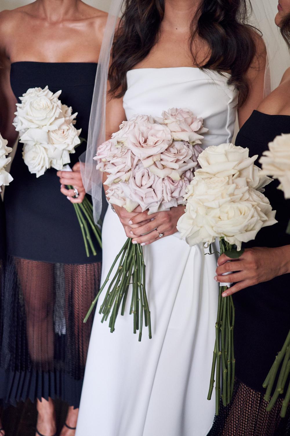 Bride holding her pink roses bouquet and bridesmaids holding their cream roses bouquet