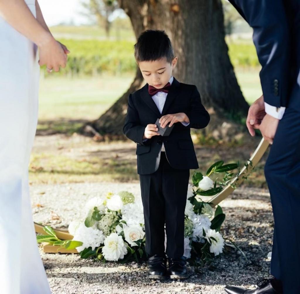 Little boy in suit opening ring box as ring bearer at wedding