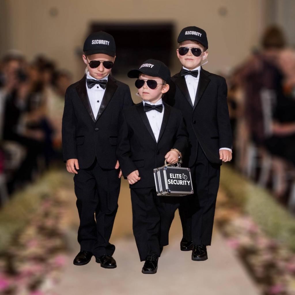 3 young boys dressed in suits and walking down the aisle as ring security at wedding