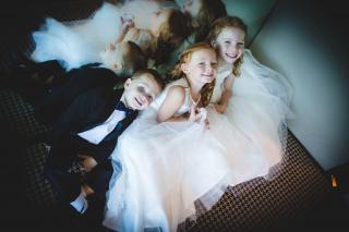 2 flowergirls and 1 page boy smiling together at wedding