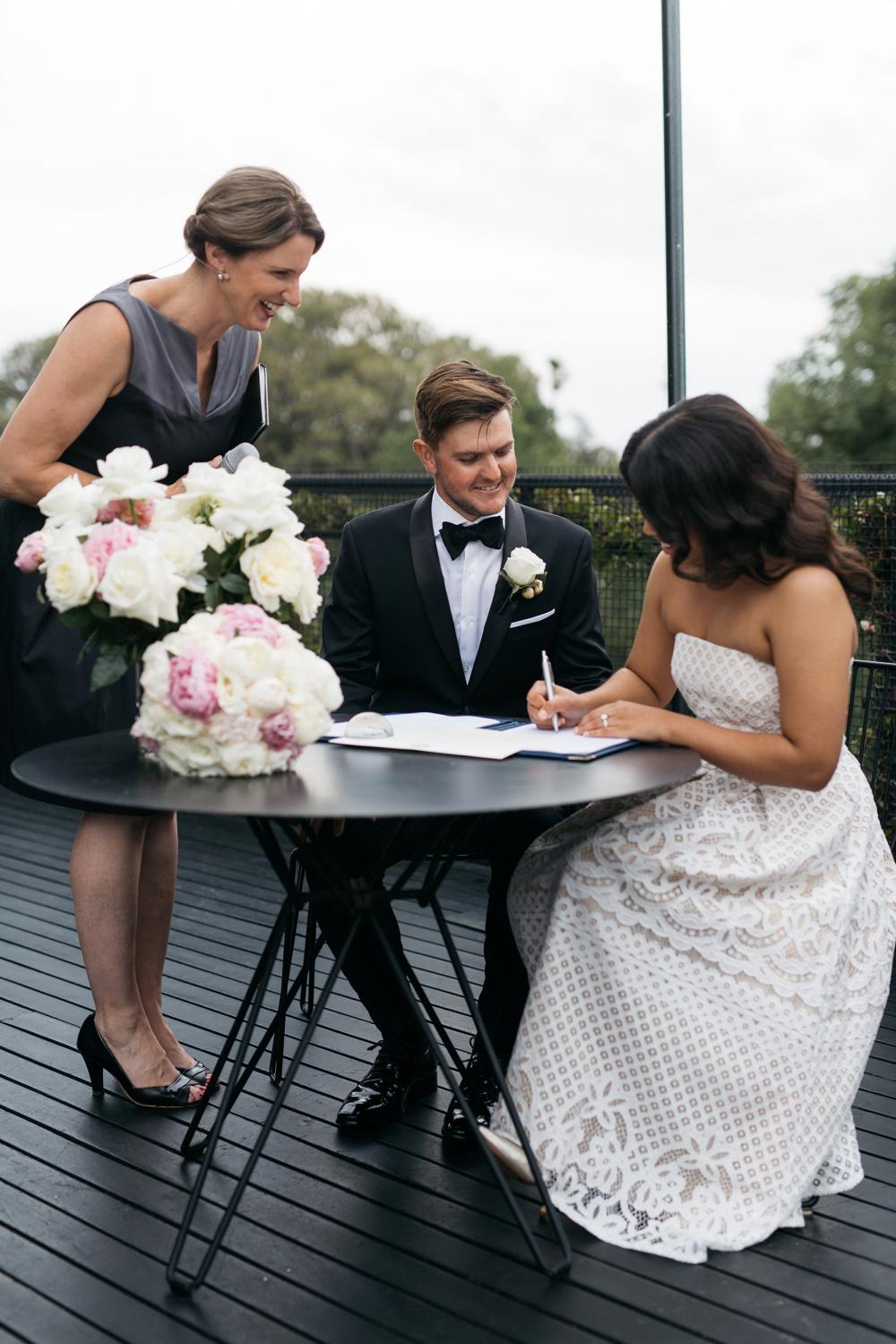 Celebrant witnesses the bride and groom signing the register during wedding ceremony