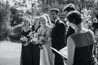 Bride, groom and bridesmaids looking at celebrant and sharing a laugh during a funny moment