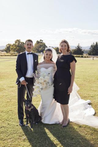 Bride + Groom posing for photo with female marriage celebrant and dog