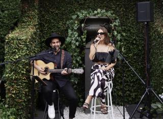 Wedding guitarist and singer performing together under green arbour