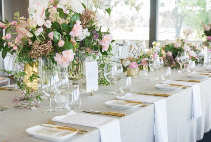 White table setting setting with pink and white flowers and gold cutlery