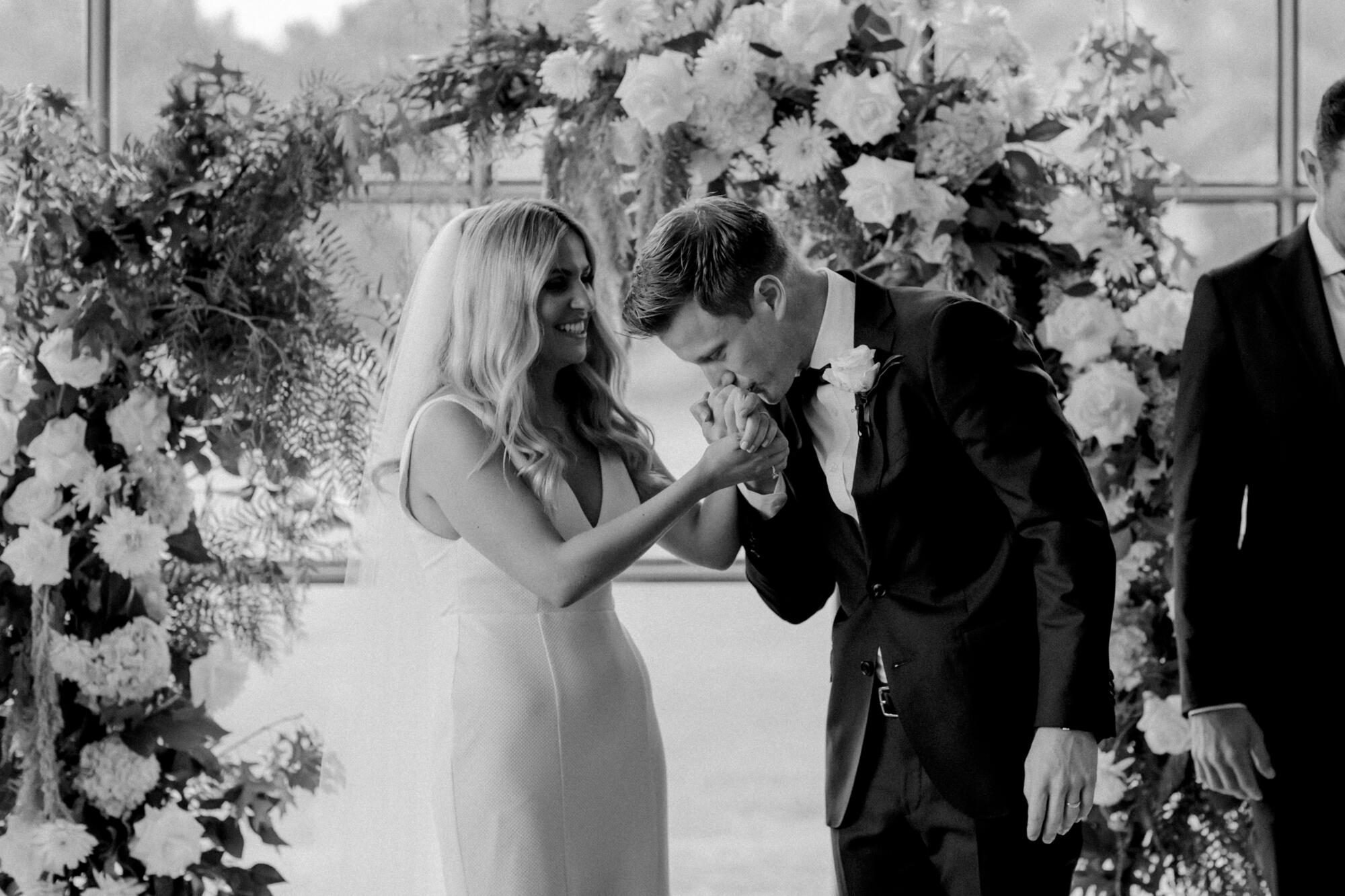 Wedding planning with Intention Groom kissing brides hand during wedding ceremony