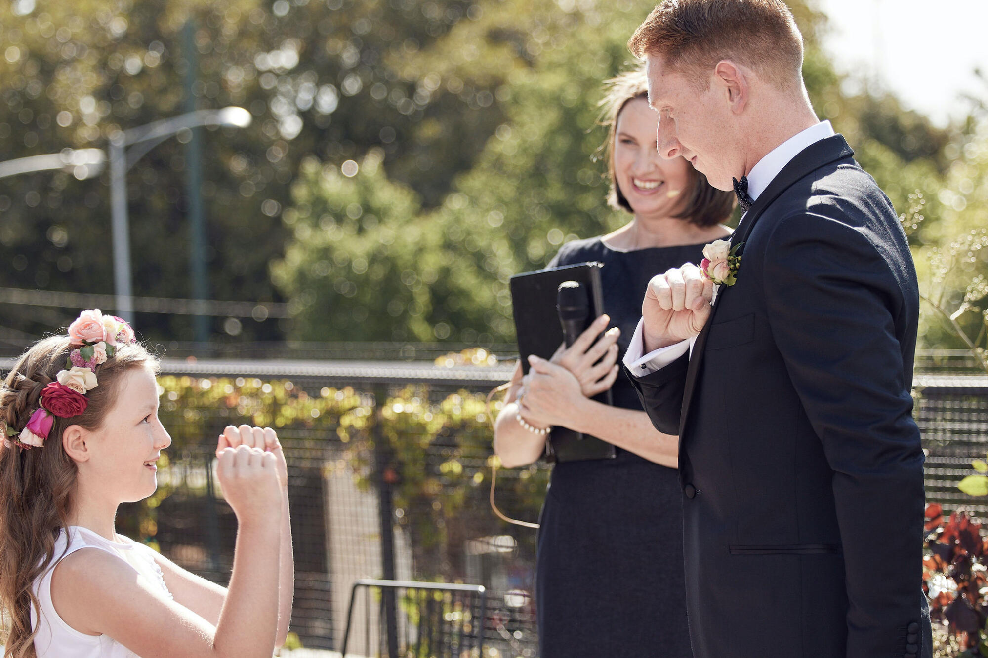 Wedding planning with intention Groom and flower girl perform secret handshake in front of celebrant at wedding ceremony